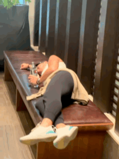 A Person Is Laying On A Bench With A Bottle Of Water In Their Hand . GIF