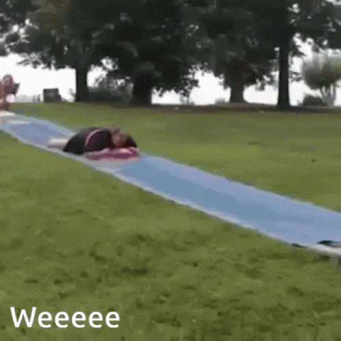 A Person Is Laying On A Blue Slide With The Words Weeeee Below It GIF