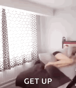 A Person Is Laying On A Couch In A Bedroom With The Words `` Get Up '' Written On It . GIF