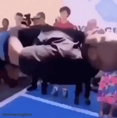 A Person Is Laying On A Couch In Front Of A Crowd . GIF
