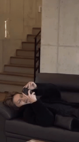 A Person Is Laying On A Couch Talking On A Cell Phone GIF