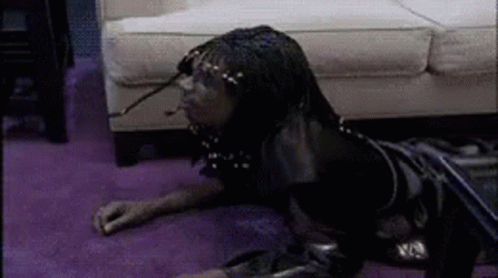 A Person Is Laying On The Floor In Front Of A Couch . GIF