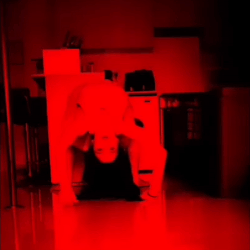 A Person Is Laying On Their Back In A Dark Room With A Red Light Behind Them GIF