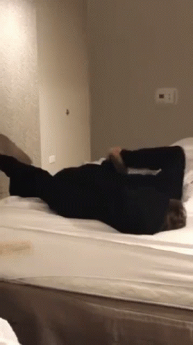 A Person Is Laying On Their Back On A Bed In A Bedroom GIF