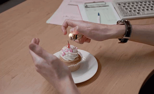 A Person Is Lighting A Cupcake With A Lighter GIF