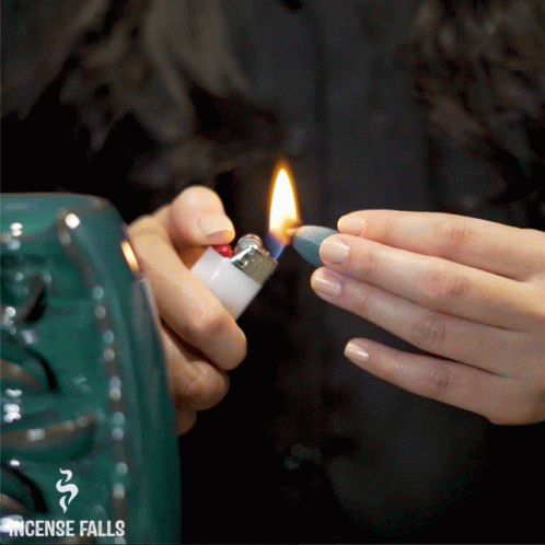 A Person Is Lighting A Lighter In Front Of A Sign That Says ' Incense Falls ' GIF