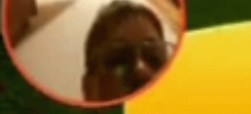 A Person Is Looking At Their Reflection In A Round Mirror . GIF