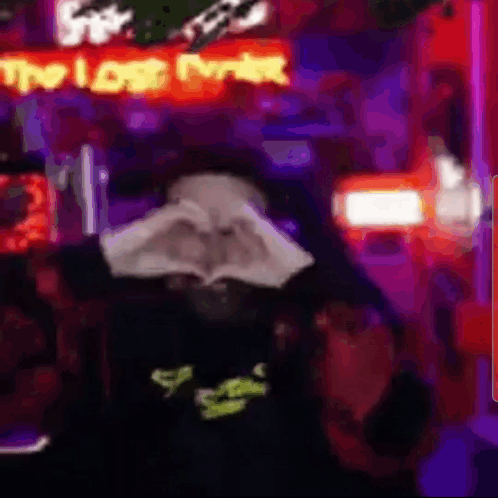 A Person Is Making A Heart Shape With Their Hands In Front Of A Neon Sign That Says `` The Lost Ever '' . GIF