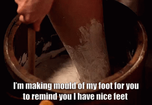 A Person Is Making Mould Of Their Foot In A Wooden Bucket . GIF