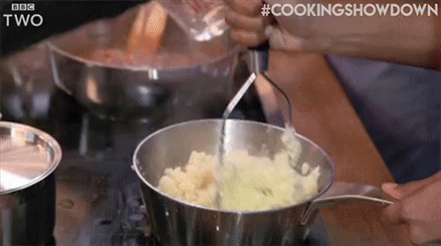 A Person Is Mashing Potatoes In A Pot . GIF