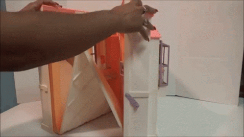 A Person Is Opening A Doll House With A Key GIF