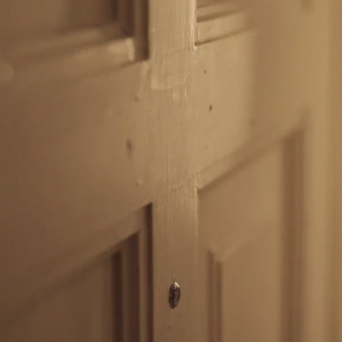 a person is opening a door with a knife in their hand .
