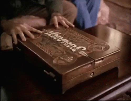 A Person Is Opening A Wooden Box That Says Jurassic Park On It GIF