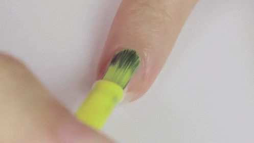 A Person Is Painting Their Nails With A Yellow Nail Polish Brush . GIF