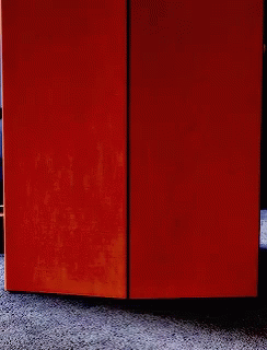 A Person Is Peeking Out From Behind A Door GIF