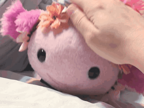 a person is petting a stuffed animal with a flower on its head