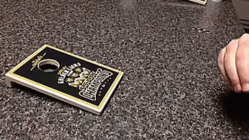 A Person Is Playing A Game Of Cornhole On A Counter Top GIF