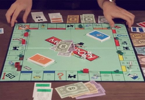 A Person Is Playing A Monopoly Game With Money And Cards GIF