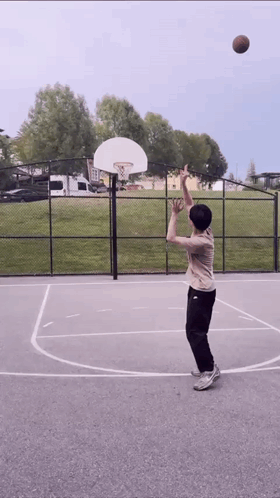 A Person Is Playing Basketball On A Court With A Basketball Hoop In The Background GIF