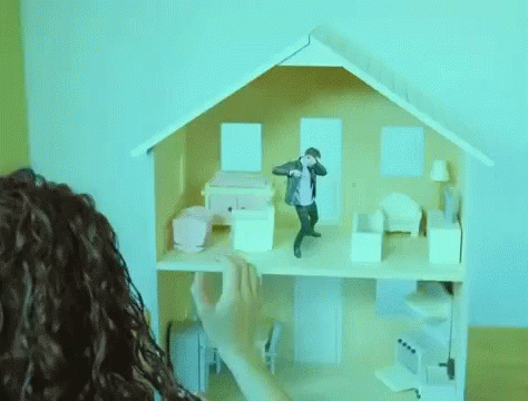A Person Is Playing With A Doll House With A Man Standing On The Top Floor . GIF