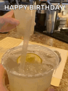 A Person Is Pouring A Drink Into A Plastic Cup With Ice And A Lime Slice . GIF