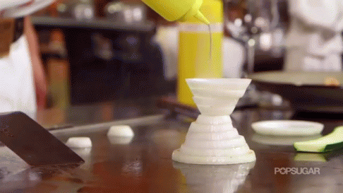 A Person Is Pouring A Yellow Liquid Into A White Container With The Word Popsugar On The Bottom GIF