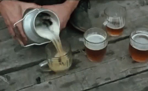 A Person Is Pouring Beer Into Four Mugs On A Wooden Table GIF