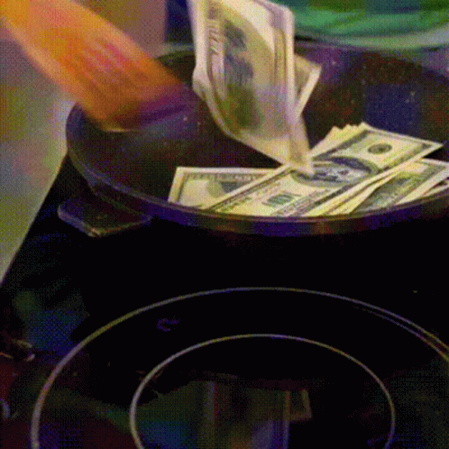 A Person Is Pouring Money Into A Frying Pan That Has Twenty Dollar Bills On It GIF