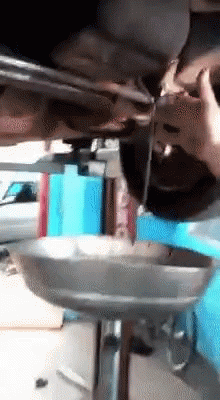A Person Is Pouring Oil Into A Metal Tray Under A Car GIF