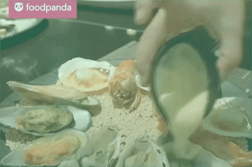 A Person Is Pouring Sauce Into A Plate Of Seafood With A Foodpanda Logo In The Background GIF