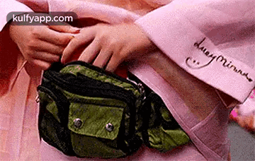A Person Is Putting Something In A Green Fanny Pack . GIF