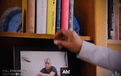 A Person Is Reaching For A Picture Of A Man On A Tv Screen GIF