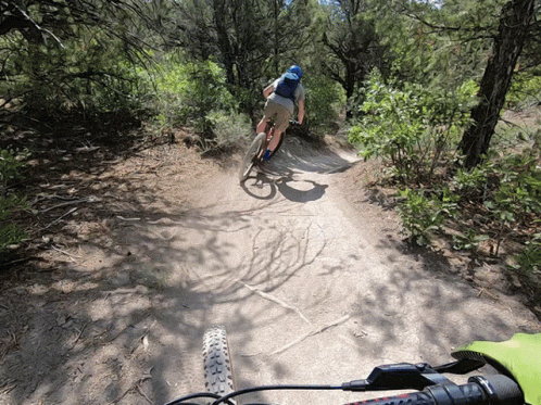 A Person Is Riding A Bike Down A Dirt Path GIF
