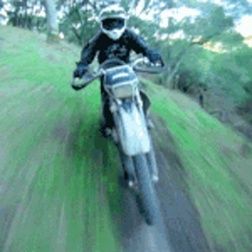 A Person Is Riding A Dirt Bike On A Grassy Hill GIF