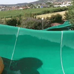 A Person Is Riding A Green Water Slide In A Park GIF