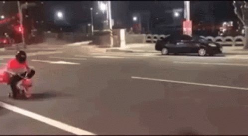 A Person Is Riding A Motorcycle On A Street At Night . GIF