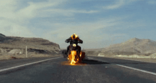 A Person Is Riding A Motorcycle That Is On Fire On The Road GIF