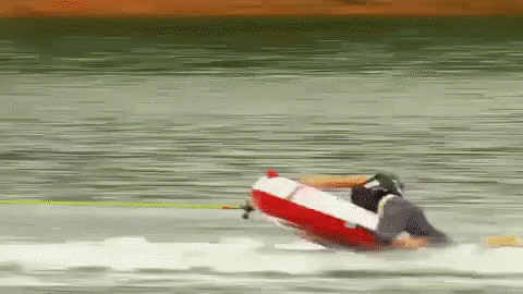 A Person Is Riding A Red And White Raft On A Lake GIF