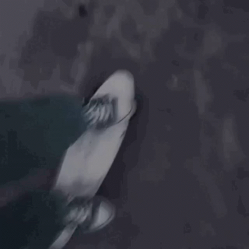 A Person Is Riding A Skateboard Down A Dark Street . GIF