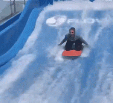 A Person Is Riding A Surfboard Down A Water Slide In The Water . GIF