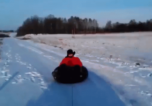 A Person Is Riding Down A Snow Covered Road On A Snow Tube GIF