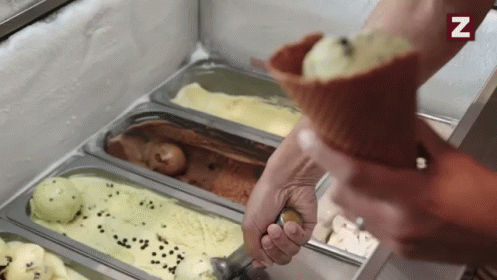 A Person Is Scooping Ice Cream Out Of A Cone With A Spoon .. GIF