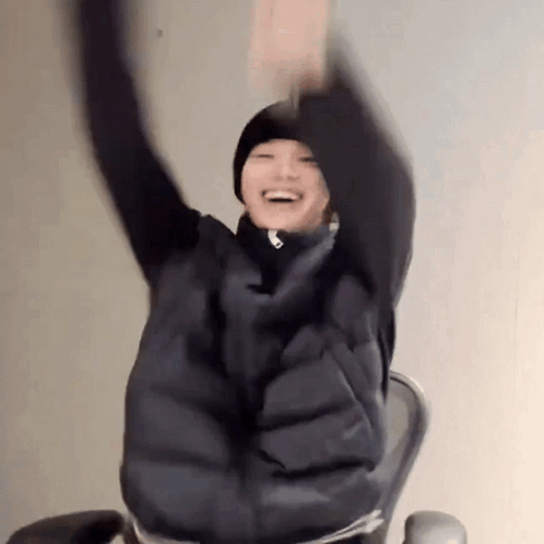 A Person Is Sitting In A Chair With Their Arms Up In The Air . GIF