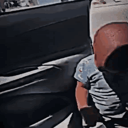 A Person Is Sitting In The Back Seat Of A Car Looking Out The Window . GIF