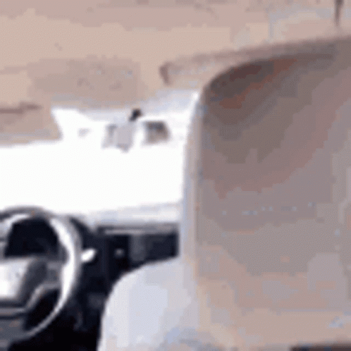 A Person Is Sitting In The Driver 'S Seat Of A Car And Looking Out The Window . GIF