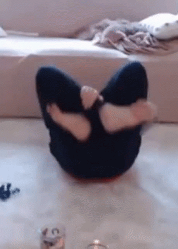 A Person Is Sitting On The Floor With Their Legs Crossed And A Candle In The Background . GIF