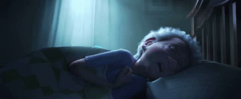 A Person Is Sleeping In A Bed With A Blue Light Shining Through The Window . GIF