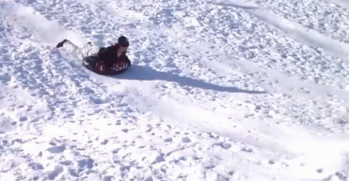 A Person Is Sliding Down A Snowy Hill On A Snow Tube GIF