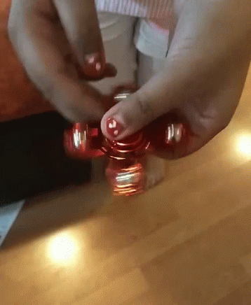 A Person Is Spinning A Red Fidget Spinner In Their Hand GIF