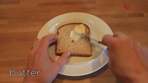 A Person Is Spreading Butter On A Piece Of Bread GIF